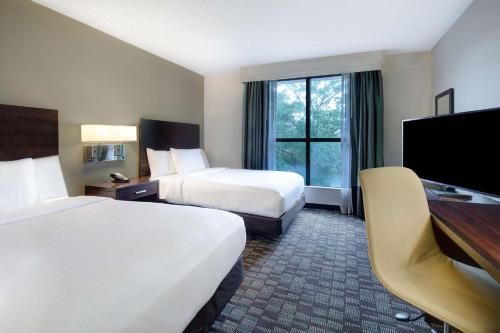 um quarto de hotel com duas camas e uma televisão de ecrã plano em Embassy Suites by Hilton Jacksonville Baymeadows em Jacksonville