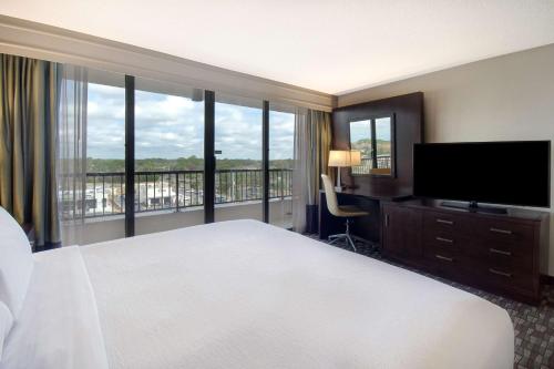 a hotel room with a large bed and a television at Embassy Suites by Hilton Jacksonville Baymeadows in Jacksonville