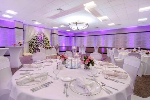 a banquet hall with white tables and white chairs at Embassy Suites by Hilton Jacksonville Baymeadows in Jacksonville
