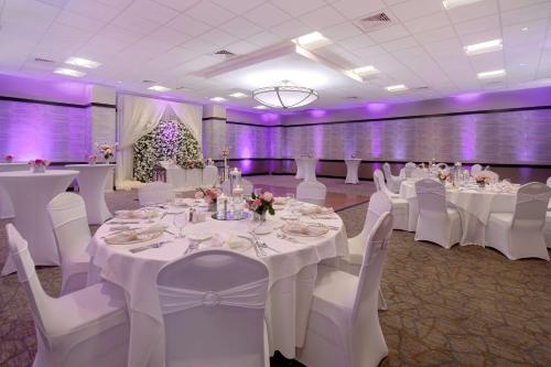 a banquet hall with white tables and white chairs at Embassy Suites by Hilton Jacksonville Baymeadows in Jacksonville