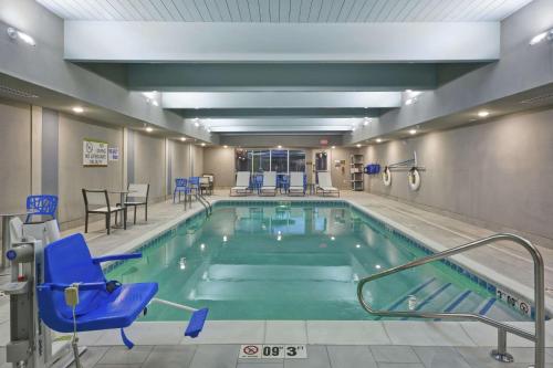a swimming pool with blue chairs and chairs in a building at Home2 Suites By Hilton Grand Rapids North in Grand Rapids