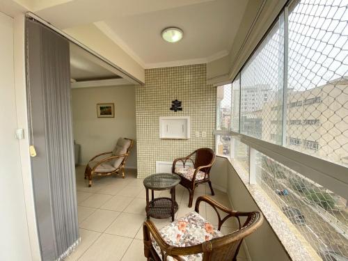 einen Balkon mit Stühlen, einem Tisch und einem Fenster in der Unterkunft Apartamento capão da canoa in Capão da Canoa