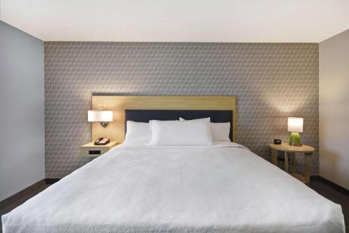a bedroom with a large white bed and two tables at Home2 Suites By Hilton Grand Rapids North in Grand Rapids