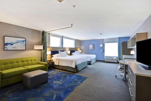 Home2 Suites By Hilton Grand Rapids North في غراند رابيدز: غرفه فندقيه بسرير واريكه