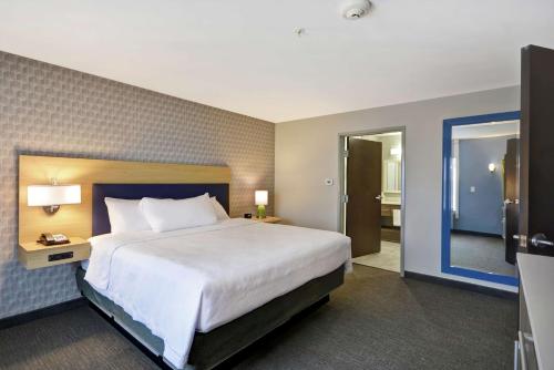 a hotel room with a large bed and a bathroom at Home2 Suites By Hilton Grand Rapids North in Grand Rapids