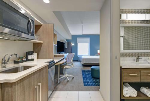 a kitchen with a sink and a room with a bed at Home2 Suites By Hilton Bordentown in Bordentown