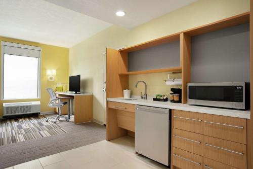 a room with a kitchen with a microwave and a desk at Home2 Suites By Hilton Elko in Elko