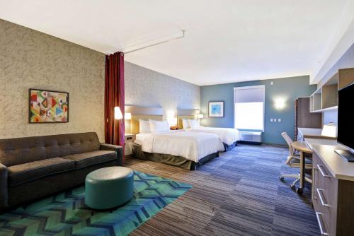 Home2 Suites by Hilton Queensbury Lake George في كوينزبيري: غرفه فندقيه بسرير واريكه