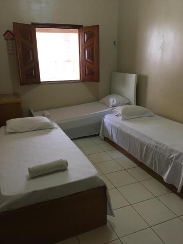 two beds in a room with a window at Casa De Benedictis Rio de Contas in Rio de Contas