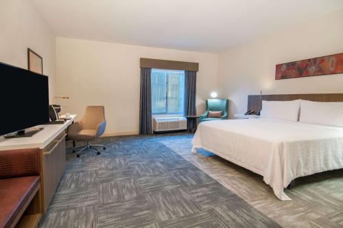 a hotel room with a bed and a flat screen tv at Hilton Garden Inn Jackson/Clinton in Clinton