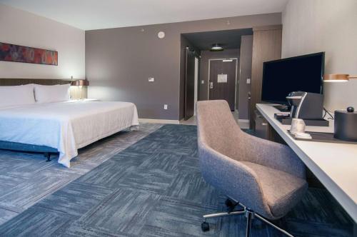 a hotel room with a bed and a desk with a computer at Hilton Garden Inn Jackson/Clinton in Clinton