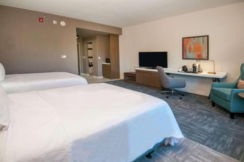 a hotel room with two beds and a desk and a television at Hilton Garden Inn Jackson/Clinton in Clinton