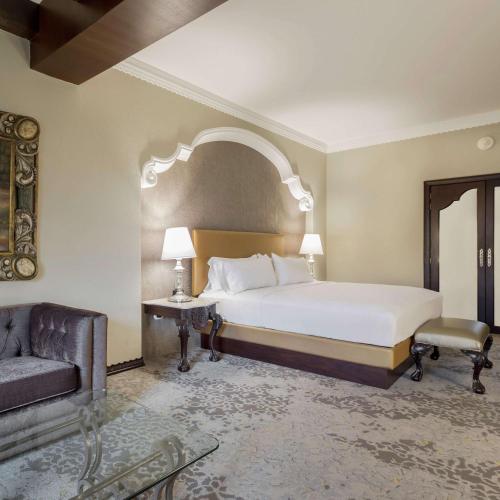 a bedroom with a bed and a chair and a couch at Hilton Guatemala City, Guatemala in Guatemala