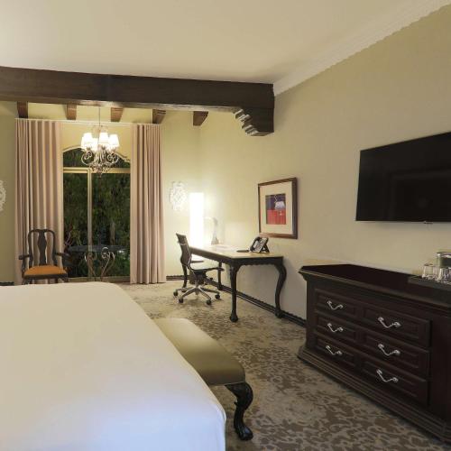 a bedroom with a bed and a desk and a television at Hilton Guatemala City, Guatemala in Guatemala