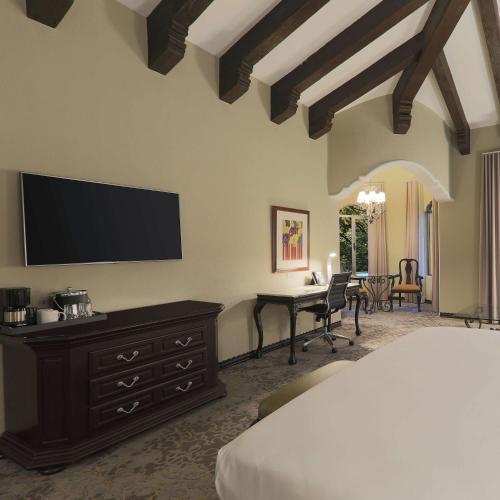 a bedroom with a bed and a desk with a television at Hilton Guatemala City, Guatemala in Guatemala