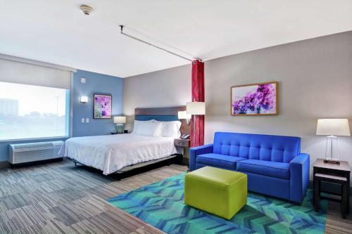 Home2 Suites By Hilton Springdale في سبرينغدل: غرفة فندق بسرير واريكة زرقاء