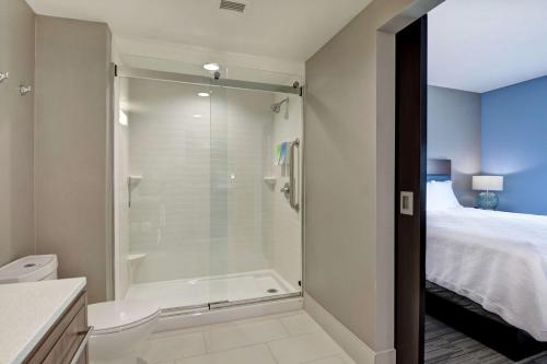 a bathroom with a shower and a toilet and a bed at Home2 Suites By Hilton Springdale in Springdale