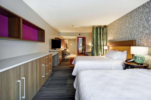 una camera d'albergo con due letti e una televisione di Home2 Suites By Hilton Terre Haute a Terre Haute