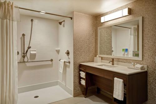 a bathroom with a sink and a shower and a mirror at Home2 Suites By Hilton Terre Haute in Terre Haute