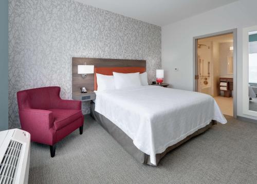 - une chambre avec un grand lit et une chaise rouge dans l'établissement Home2 Suites By Hilton Hagerstown, à Hagerstown