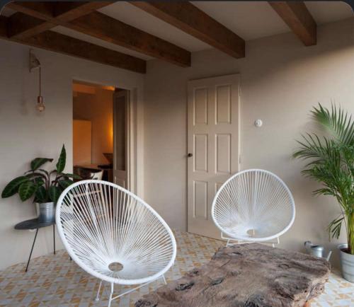 two white chairs sitting in a room with plants at Old Luxury Home in São Mamede de Infesta