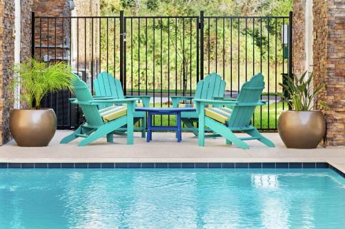 a patio with chairs and a table and a pool at Home2 Suites By Hilton Houston-Pearland, Tx in Pearland