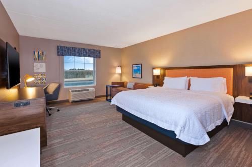 um quarto de hotel com uma cama e uma televisão de ecrã plano em Hampton Inn Cape Cod Canal em Buzzards Bay