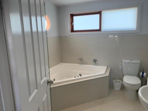 a white bathroom with a tub and a toilet at Beach Park Phillip Island - Apartments in Cowes