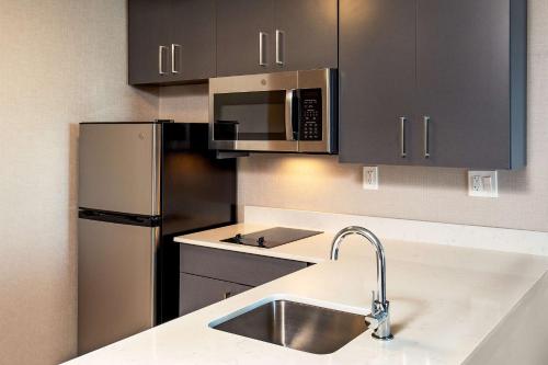 a kitchen with a sink and a stainless steel refrigerator at DoubleTree by Hilton Washington DC North/Gaithersburg in Gaithersburg