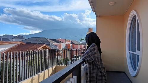 Una mujer parada en un balcón con vistas a la ciudad en Azizah's Syariah Homestay, en Padangluar