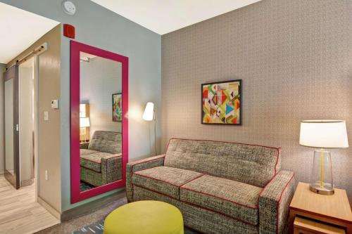a living room with a couch and a mirror at Home2 Suites By Hilton Jacksonville South St Johns Town Ctr in Jacksonville