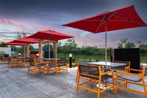 a patio with tables and chairs with red umbrellas at Hilton Garden Inn By Hilton Fort Wayne North in Sunnybrook Acres