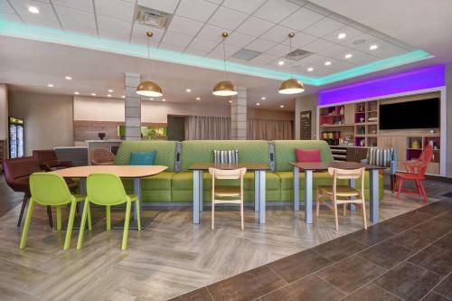 a waiting area with tables and chairs in a library at Home2 Suites by Hilton Wichita Northeast in Wichita