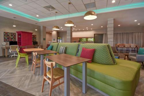 a waiting room with a green couch and tables at Home2 Suites by Hilton Wichita Northeast in Wichita