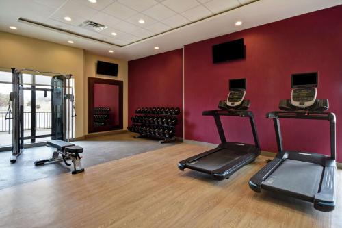 a gym with cardio equipment in a room with red walls at Home2 Suites by Hilton Wichita Northeast in Wichita