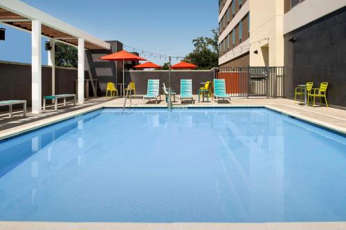 a large swimming pool with chairs and umbrellas at Home2 Suites By Hilton Clovis Fresno Airport in Clovis
