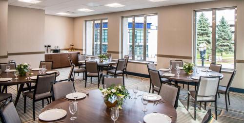 a dining room with tables and chairs and windows at Hilton Garden Inn Flint Downtown in Flint