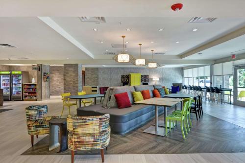 a living room with a couch and tables and chairs at Home2 Suites By Hilton Jacksonville South St Johns Town Ctr in Jacksonville