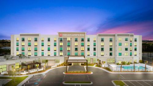 a large white hotel with a parking lot at Hilton Garden Inn Harlingen Convention Center, Tx in Harlingen