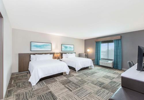 a hotel room with two beds and a flat screen tv at Hilton Garden Inn Harlingen Convention Center, Tx in Harlingen