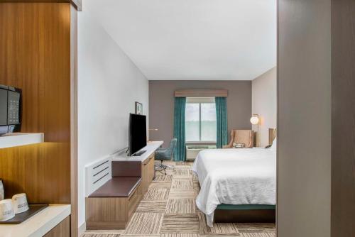 a hotel room with a bed and a flat screen tv at Hilton Garden Inn Harlingen Convention Center, Tx in Harlingen