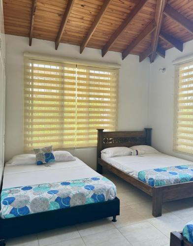 two beds in a room with windows with blinds at Cabaña La Betica in Villavicencio