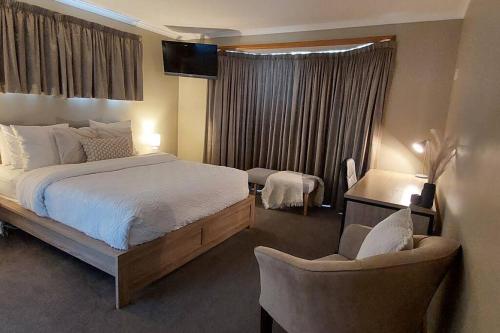 a bedroom with a bed and two chairs and a window at Valentine House in Hadspen