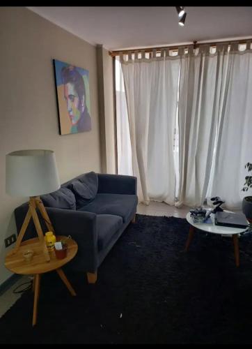 uma sala de estar com um sofá azul e uma mesa em Departamento por días em Arica