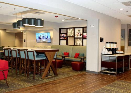 a restaurant with a bar with chairs and a table at Hampton Inn Lexington in Lexington