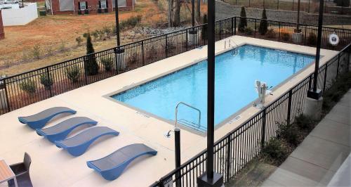 a swimming pool with two blue chairs and a fence at Hampton Inn Lexington in Lexington