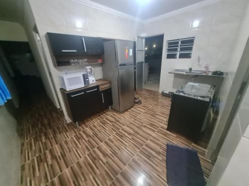 a kitchen with a stainless steel refrigerator and a wooden floor at Casa mobiliada para descanso e para viajantes se hospedarem por temporada in Bayeux
