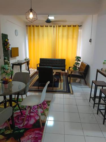 een woonkamer met tafels en stoelen en gele gordijnen bij Bidadari Pool in Port Dickson