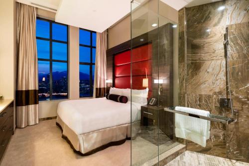 Delta Hotels by Marriott Burnaby Conference Centre في برنابي: غرفة نوم مع سرير ودش زجاجي