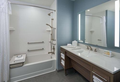 Home2 Suites By Hilton Pompano Beach Pier, Fl في بومبانو بيتش: حمام مع حوض وحوض ومرآة